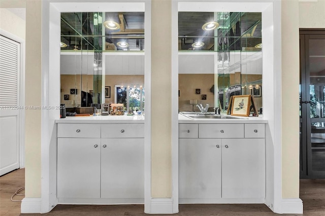 bar with wood-type flooring, sink, and white cabinetry