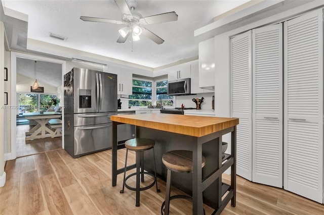 kitchen with black appliances, butcher block countertops, a wealth of natural light, and white cabinetry