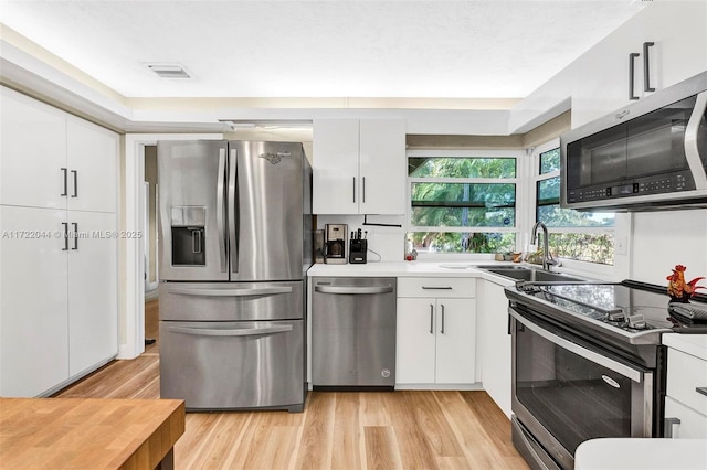 kitchen featuring sink, stainless steel appliances, light hardwood / wood-style flooring, and white cabinetry