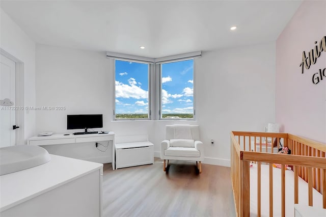 bedroom with a nursery area and light hardwood / wood-style floors