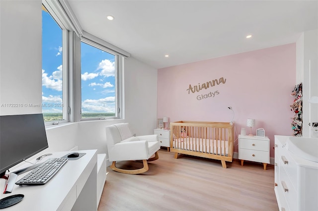 bedroom featuring a crib and light hardwood / wood-style floors