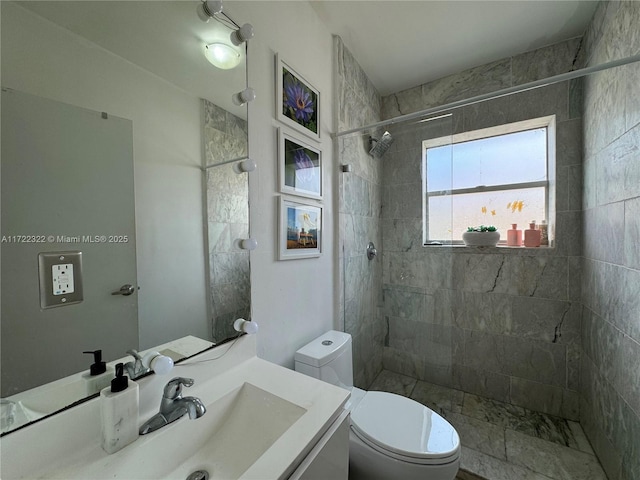 bathroom with a tile shower, vanity, and toilet