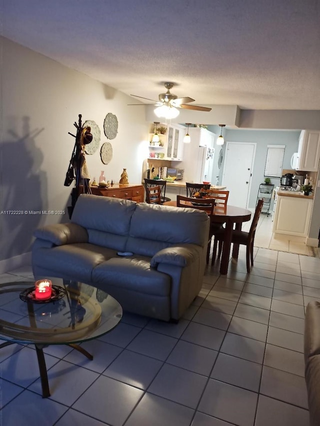 tiled living room with ceiling fan and a textured ceiling