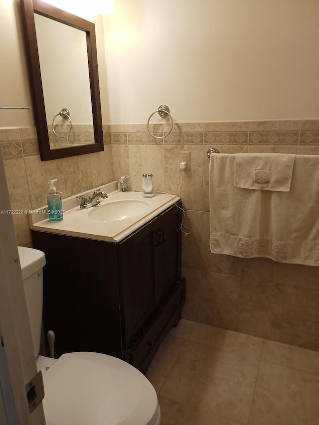 bathroom featuring tile patterned flooring, vanity, toilet, and tile walls