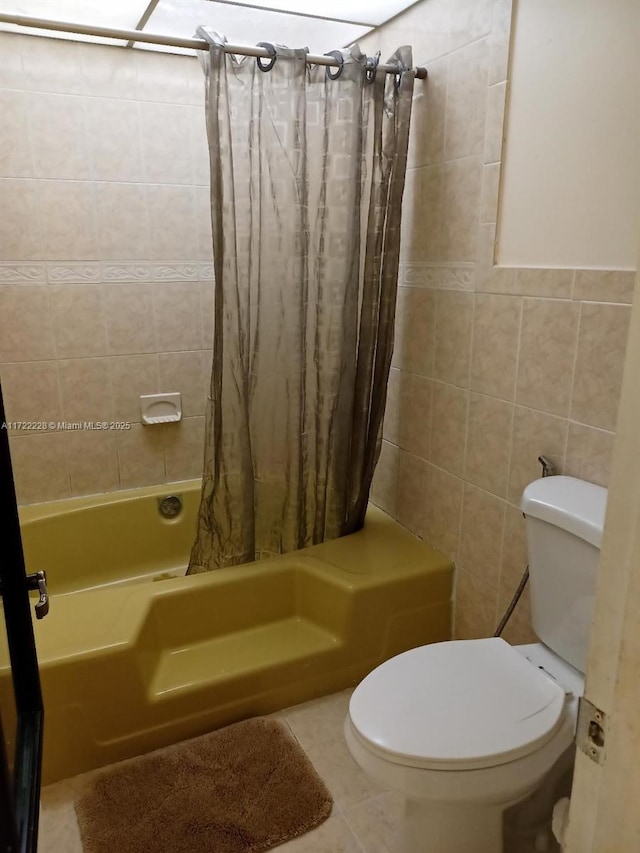 bathroom with toilet, shower / tub combo, tile patterned floors, and tile walls