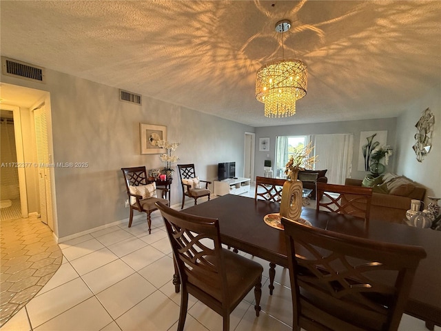 tiled dining space featuring a textured ceiling and an inviting chandelier