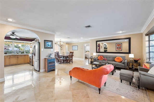 living room with a textured ceiling, ceiling fan with notable chandelier, and ornamental molding