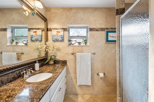 bathroom featuring tile patterned flooring, vanity, a shower with door, and tile walls