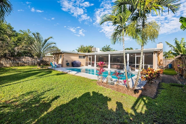 rear view of house featuring a sunroom, a fenced in pool, and a lawn