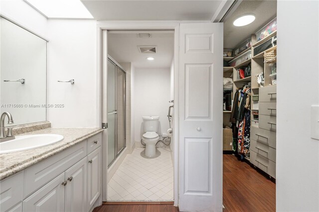 bathroom featuring vanity, toilet, wood-type flooring, and walk in shower