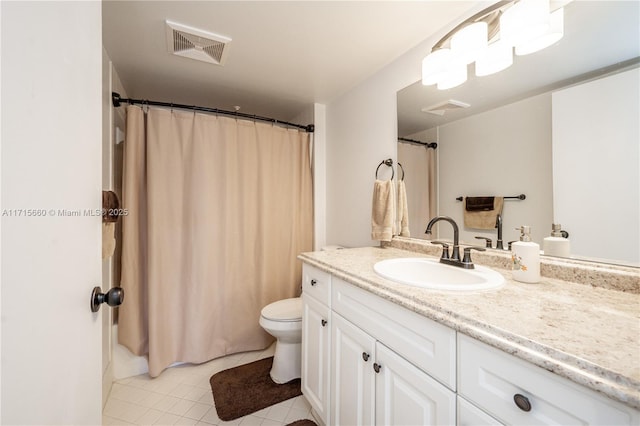 bathroom with toilet, vanity, and tile patterned floors