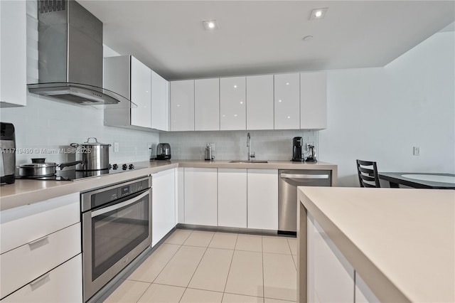 kitchen featuring wall chimney exhaust hood, white cabinetry, sink, and appliances with stainless steel finishes