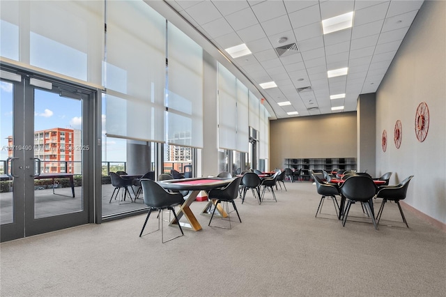 interior space with carpet flooring, a paneled ceiling, and a towering ceiling