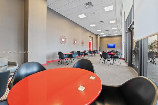 carpeted dining area with a drop ceiling