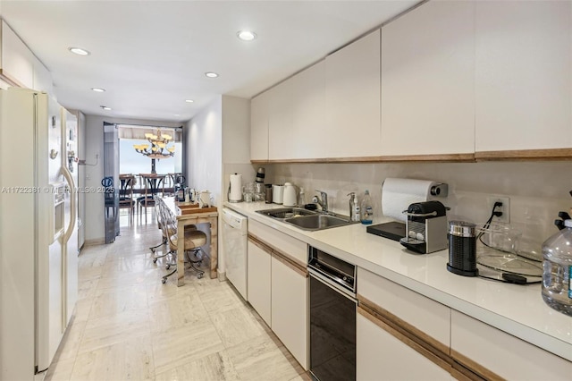 kitchen featuring sink, white cabinets, a chandelier, and white appliances