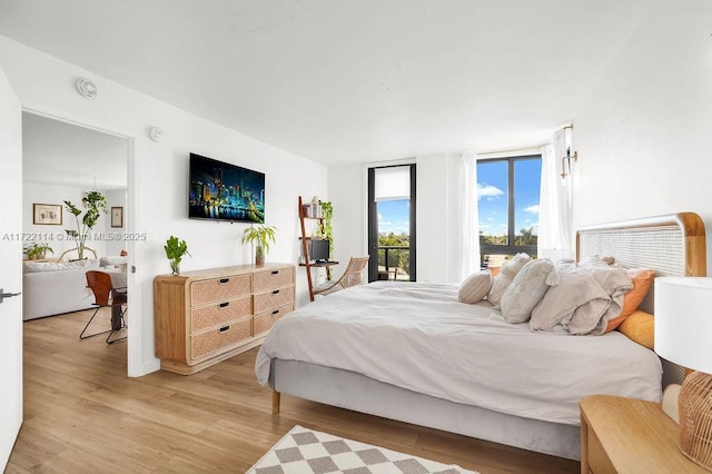 bedroom with expansive windows and light hardwood / wood-style floors