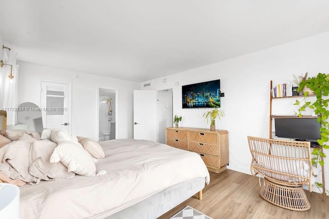 bedroom with light hardwood / wood-style floors and ensuite bath