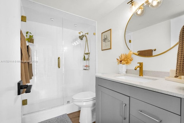 bathroom featuring hardwood / wood-style floors, vanity, toilet, and an enclosed shower