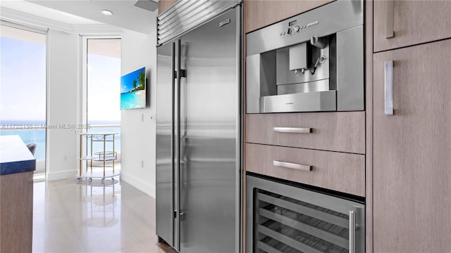 kitchen with light tile patterned floors, wine cooler, built in refrigerator, and floor to ceiling windows