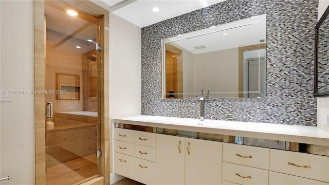 bathroom featuring backsplash, a shower with door, and vanity