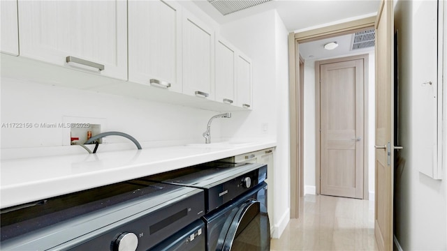 washroom featuring cabinets, light hardwood / wood-style flooring, washer and clothes dryer, and sink