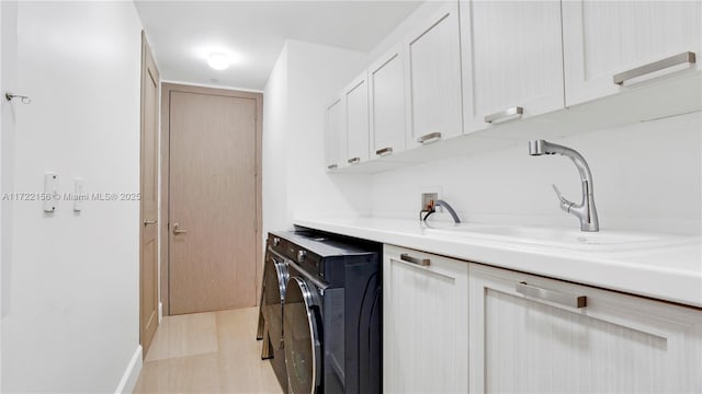 kitchen with white cabinets, light hardwood / wood-style floors, separate washer and dryer, and sink