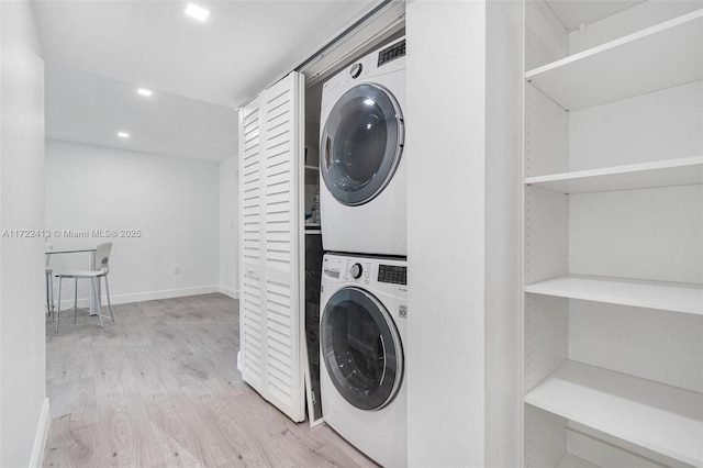 clothes washing area with stacked washer and clothes dryer and light hardwood / wood-style flooring