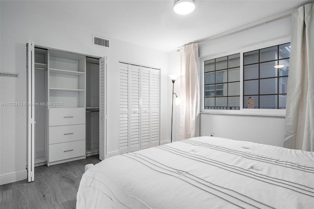 bedroom featuring dark hardwood / wood-style floors and multiple closets