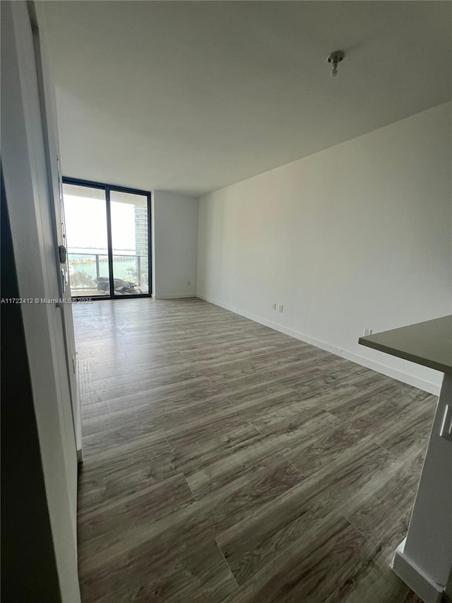 empty room with dark hardwood / wood-style floors and expansive windows