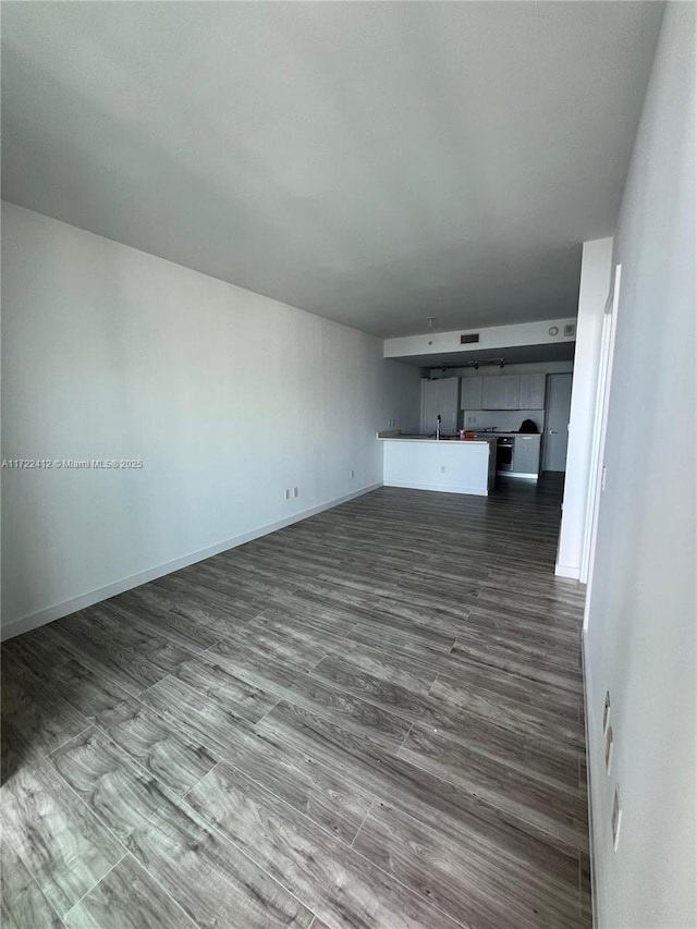 unfurnished living room featuring hardwood / wood-style floors and sink