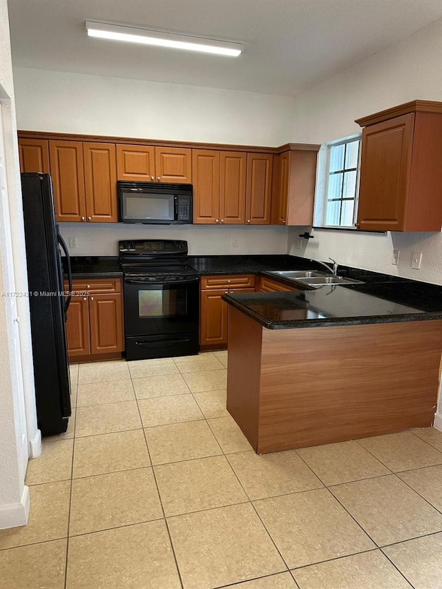 kitchen with kitchen peninsula, dark stone counters, sink, black appliances, and light tile patterned flooring