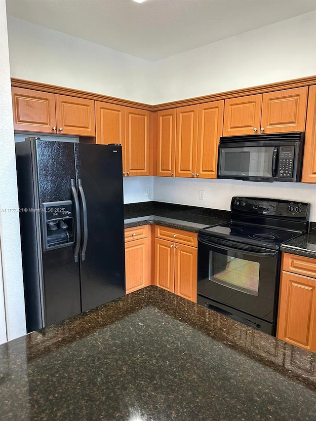 kitchen featuring dark stone counters and black appliances