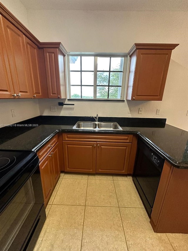 kitchen featuring dark stone counters, sink, light tile patterned floors, and black appliances