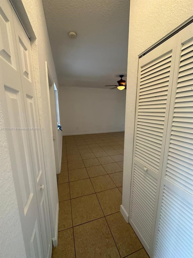 hall with light tile patterned floors and a textured ceiling