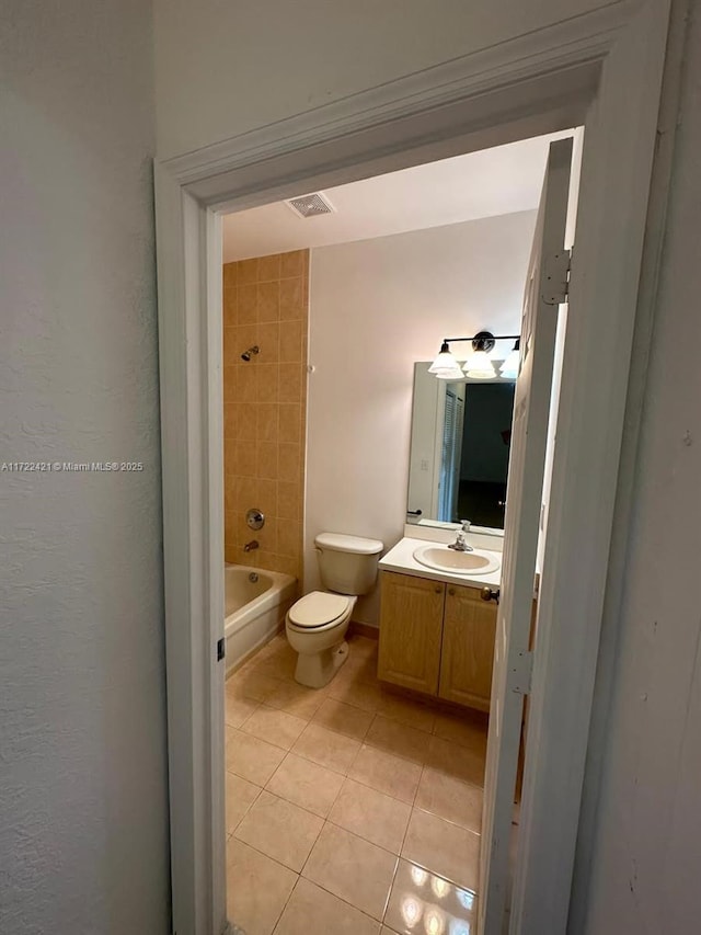 full bathroom with tile patterned floors, vanity, tiled shower / bath combo, and toilet