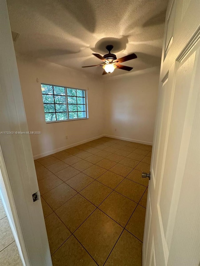 tiled spare room featuring ceiling fan and a textured ceiling