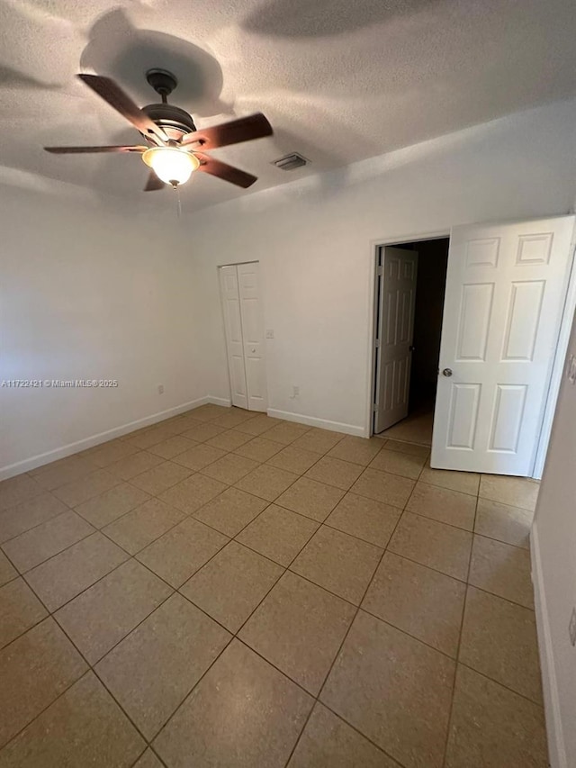 empty room featuring light tile patterned floors, a textured ceiling, and ceiling fan