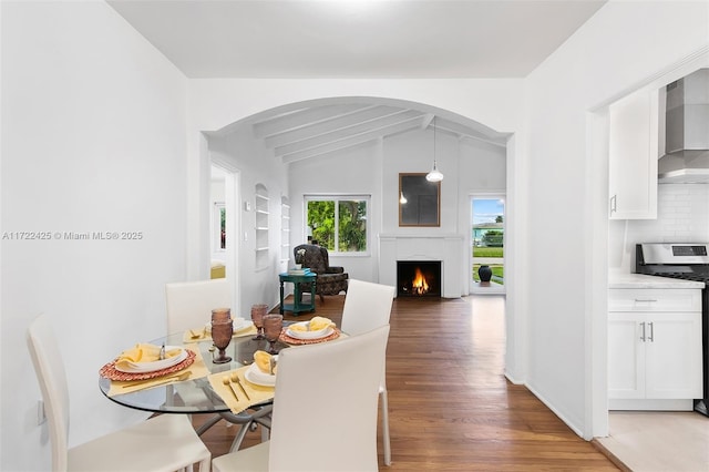 dining room featuring vaulted ceiling with beams and dark hardwood / wood-style flooring