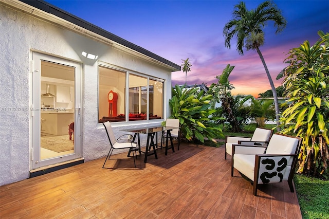 patio terrace at dusk featuring a wooden deck