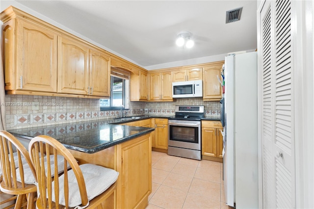 kitchen featuring kitchen peninsula, a kitchen breakfast bar, white appliances, and light tile patterned flooring