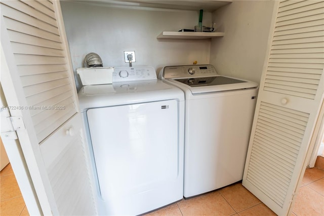 washroom with light tile patterned floors and washing machine and dryer