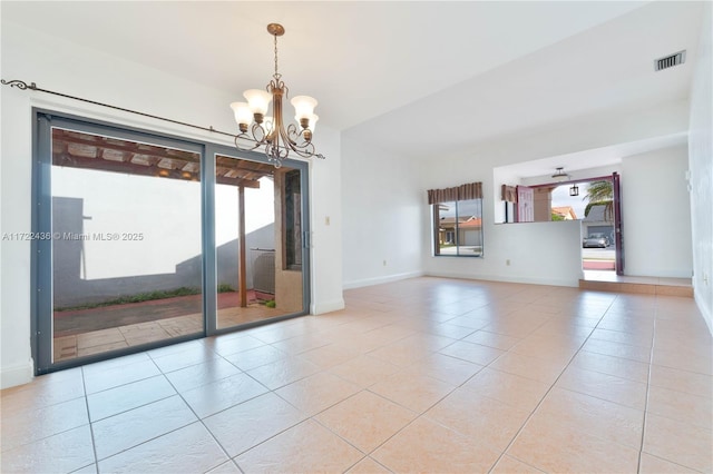 empty room with light tile patterned floors and ceiling fan with notable chandelier