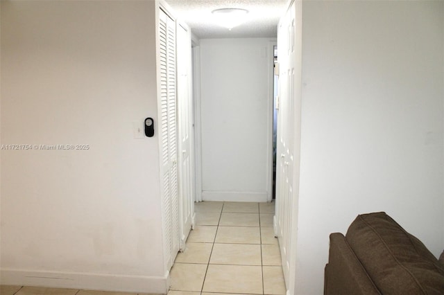 corridor featuring light tile patterned flooring and a textured ceiling