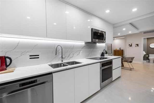 kitchen featuring sink, light stone countertops, appliances with stainless steel finishes, tasteful backsplash, and white cabinetry