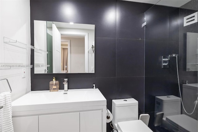 bathroom with vanity, toilet, and tile walls