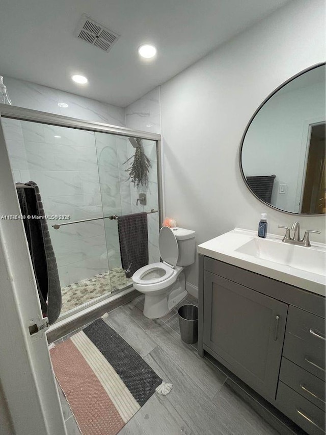 bathroom featuring vanity, toilet, and a shower with shower door