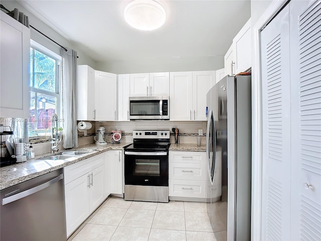 kitchen with white cabinets, decorative backsplash, appliances with stainless steel finishes, and light tile patterned floors