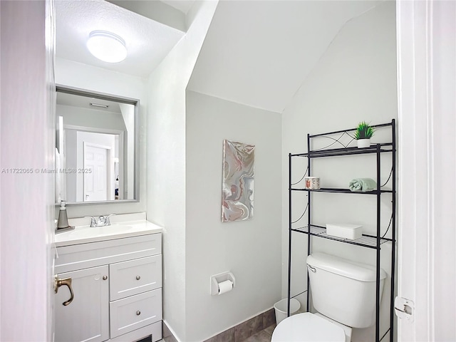 bathroom featuring toilet, lofted ceiling, and vanity