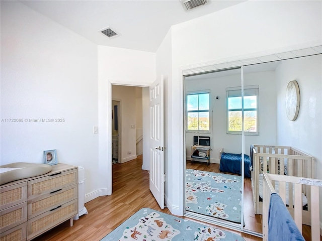 bedroom with a crib and light hardwood / wood-style floors