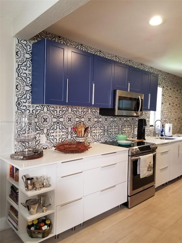 kitchen featuring backsplash, white cabinets, sink, blue cabinetry, and appliances with stainless steel finishes